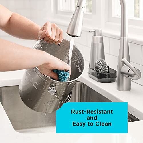 Person cleaning stainless steel bucket under faucet.