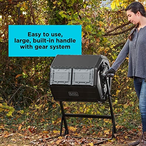 Person using a black compost tumbler bin with handle in a garden.