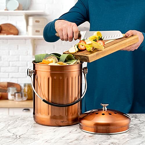 Person adding vegetable scraps to copper compost bin on kitchen counter