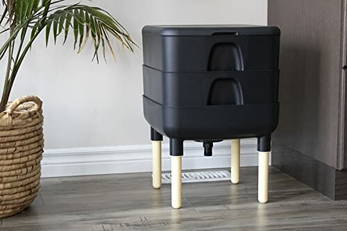 Indoor compost bin with multiple stacked trays and wooden legs.