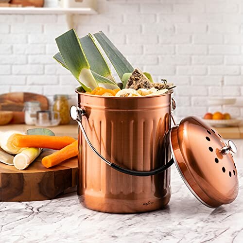 Copper compost bin filled with vegetable scraps on a kitchen counter.