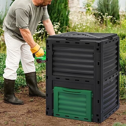 Man tending to a black and green compost bin in a garden.