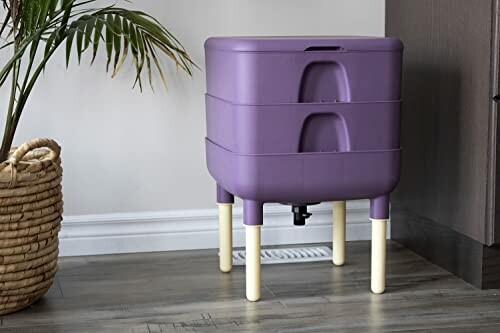 Purple indoor compost bin with legs near a plant.