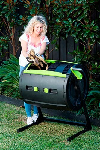 Woman using a compost tumbler in a garden